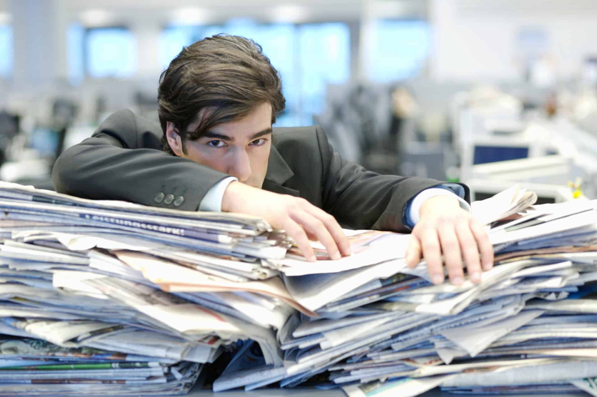businessman leaning on pile of paperwork 2026 01 11 10 01 16 utc