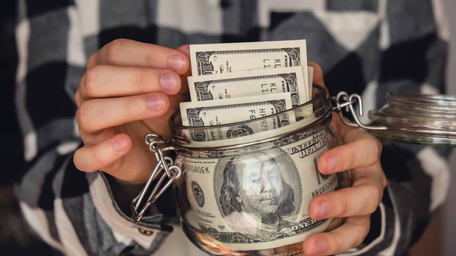 Dollar banknote saving money in glass jar. Unrecognizable woman moderate consumption and economy Collecting money. Tips. Business, finance, saving, banking and people concept. Extra money, passive income. Saving for travel, crisis, house, car, education, retirement