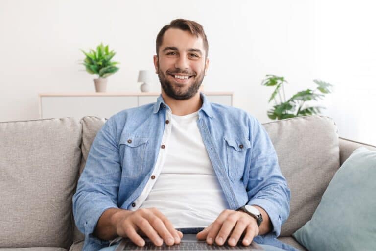 A smiling man with laptop on laps