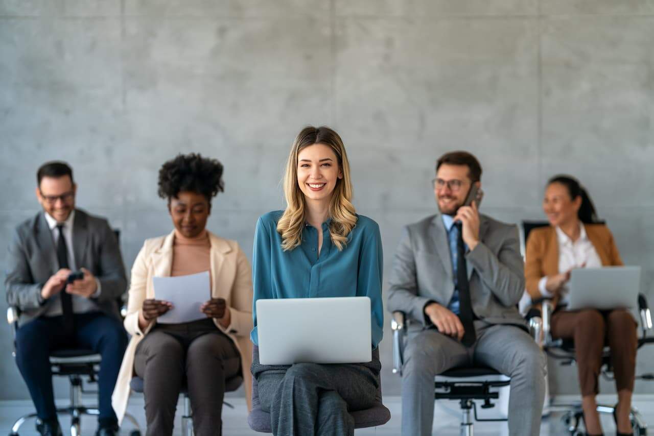 A smiling woman sitting in the middle among other business professionals
