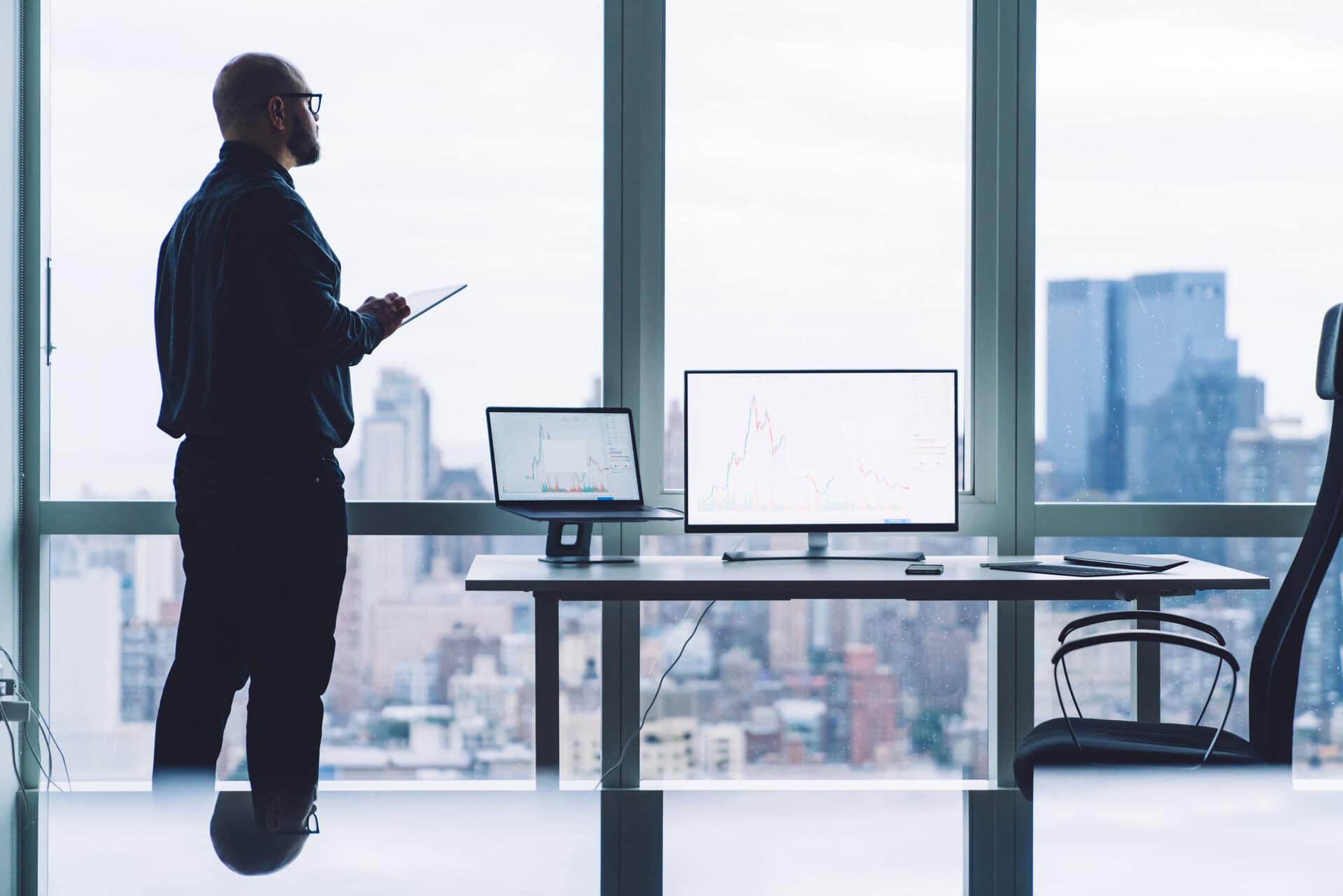 entrepreneur with tablet near computers with charts on office table