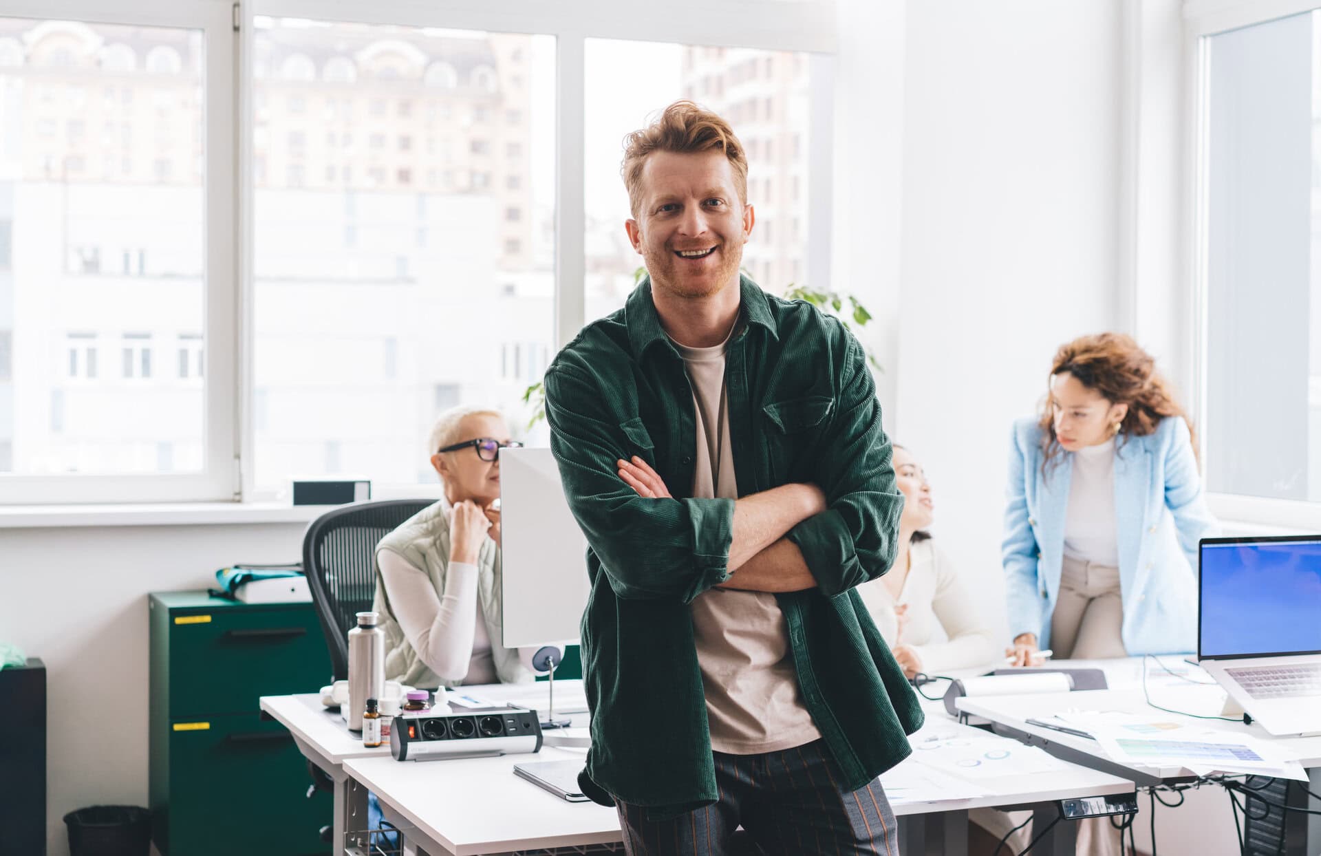 positive man with arms folded in modern workspace