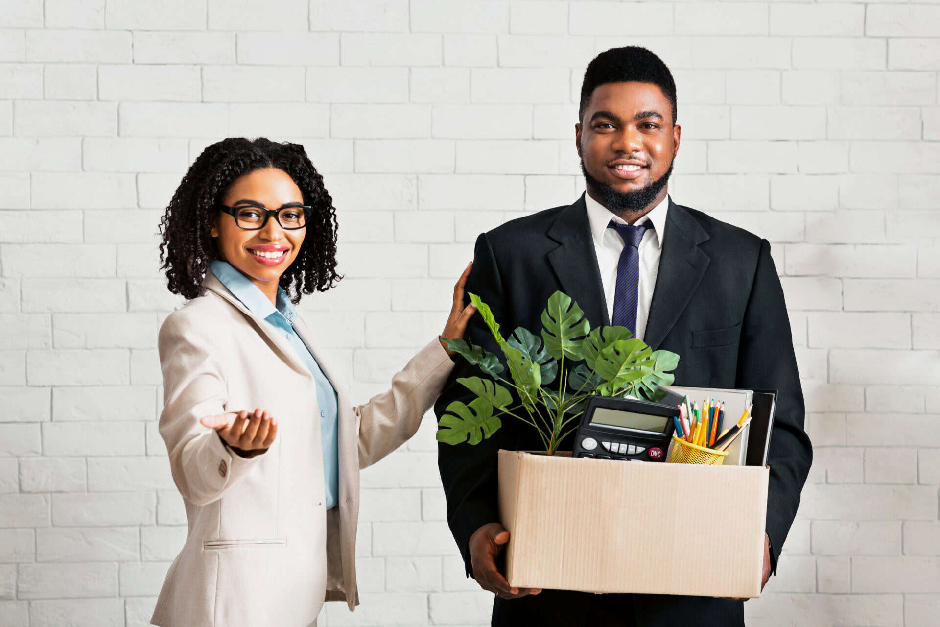 Smiling black guy with personal stuff being welcomed to company office by his lady boss. African American male employee having first day at work, getting new interesting job