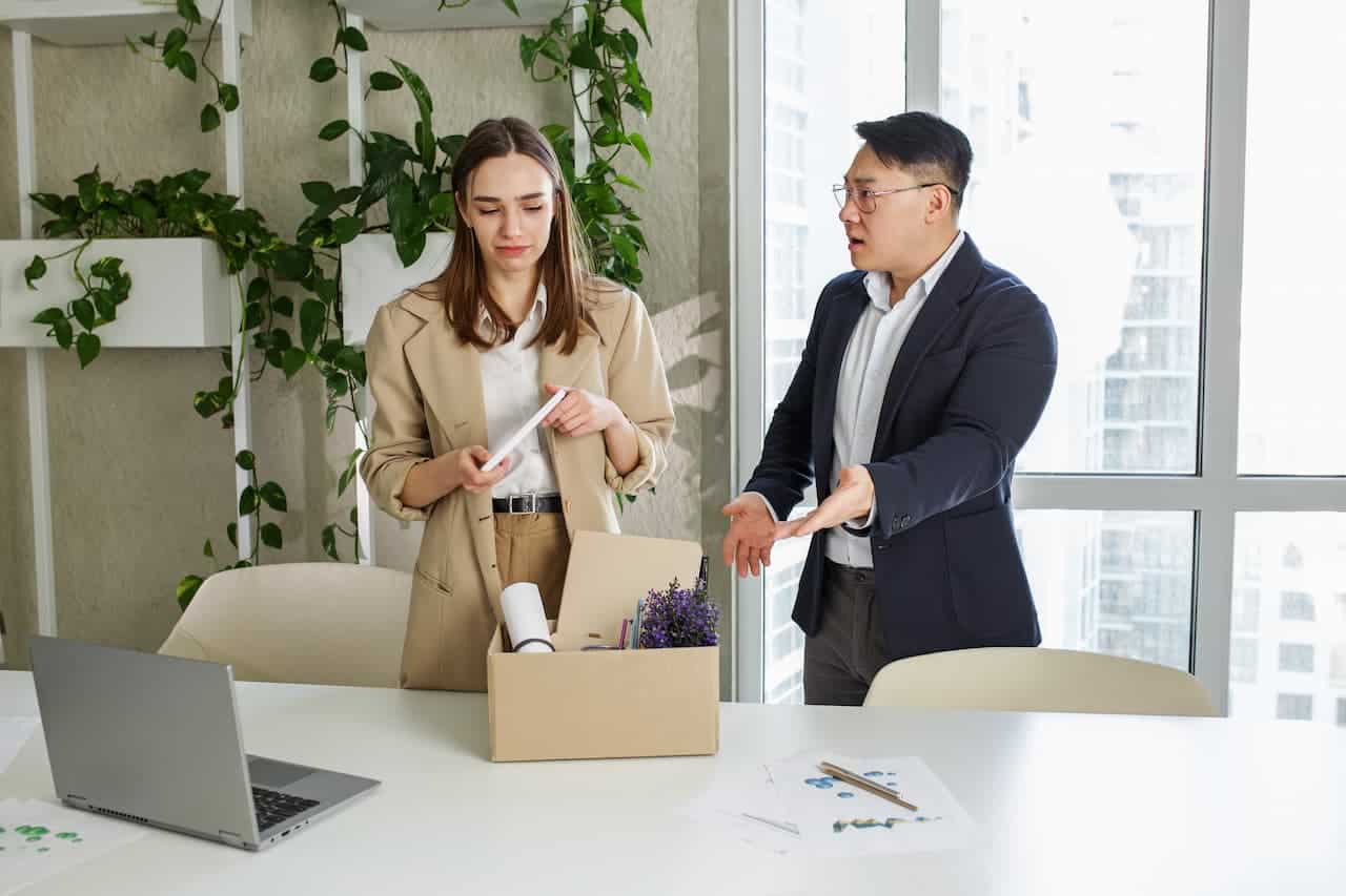 Angry asian boss firing upset female employee in modern office